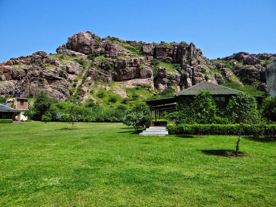 Sunrise at Camp Wild Retreat, with golden and crimson hues lighting up the rugged Aravali Hills, casting long shadows and creating a serene, tranquil atmosphere.